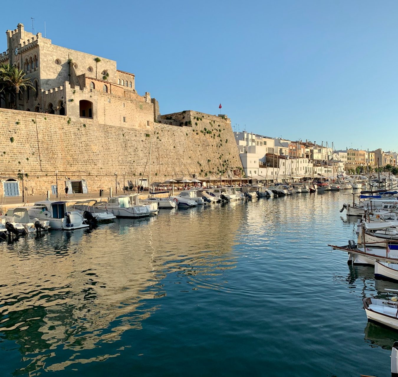 Port de Ciutadella à Minorque bordé de bateaux et de remparts historiques.