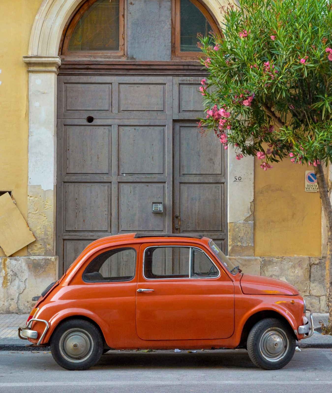 Fiat 500 ancienne dans une rue colorée lors d’un voyage en Sicile.