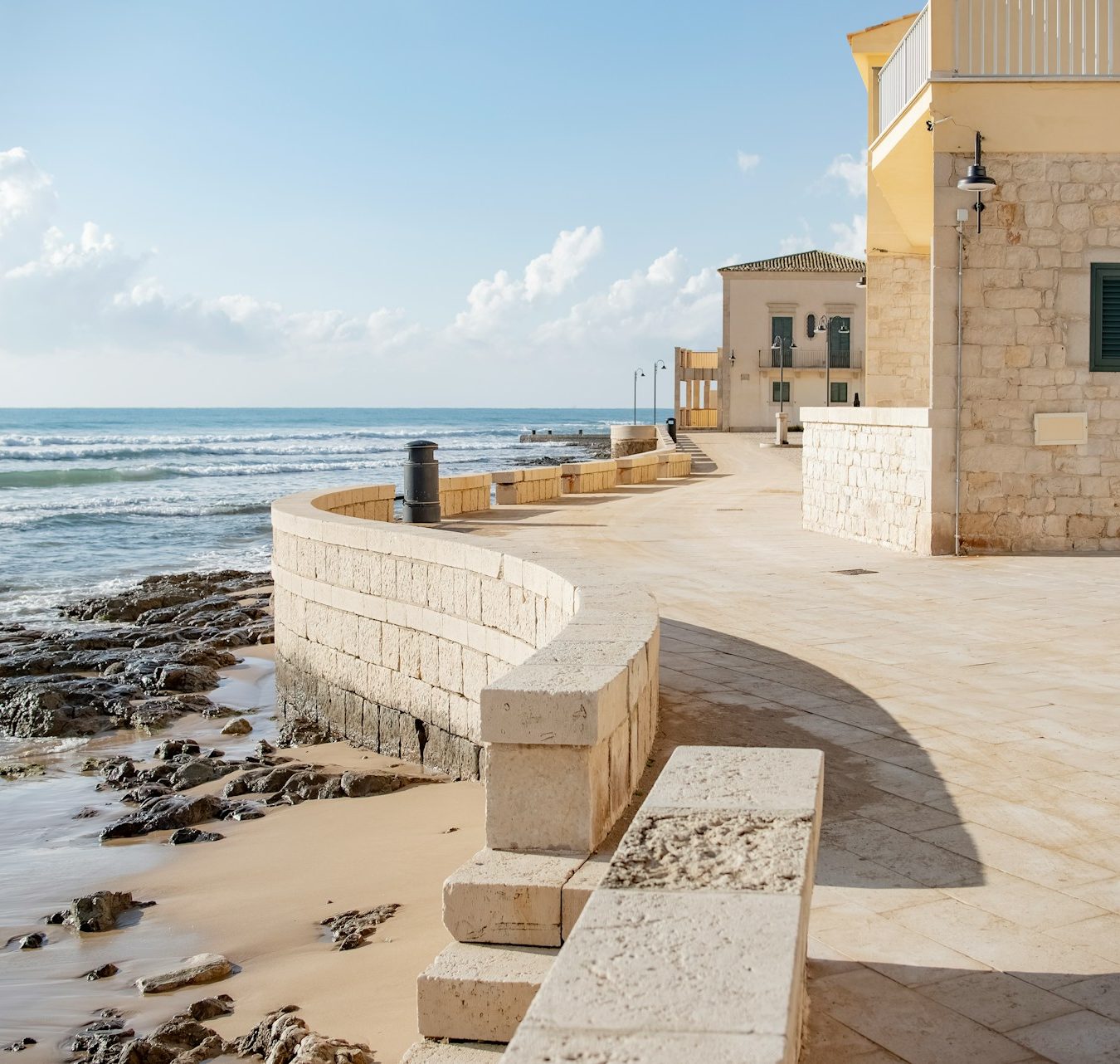 Promenade en pierre et maisons siciliennes face à la mer Méditerranée.