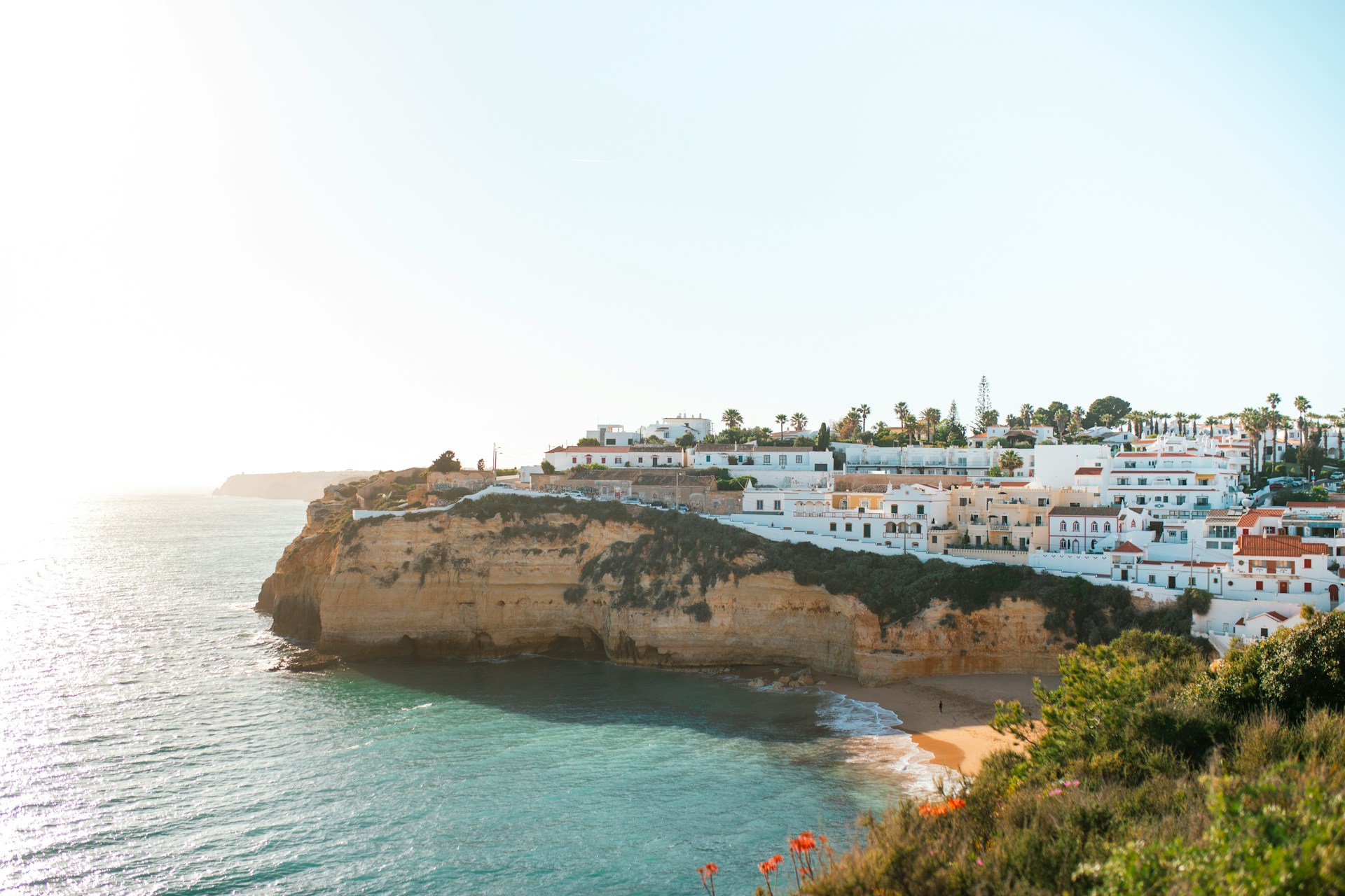 Village blanc dominant une plage et les falaises de l’Algarve
