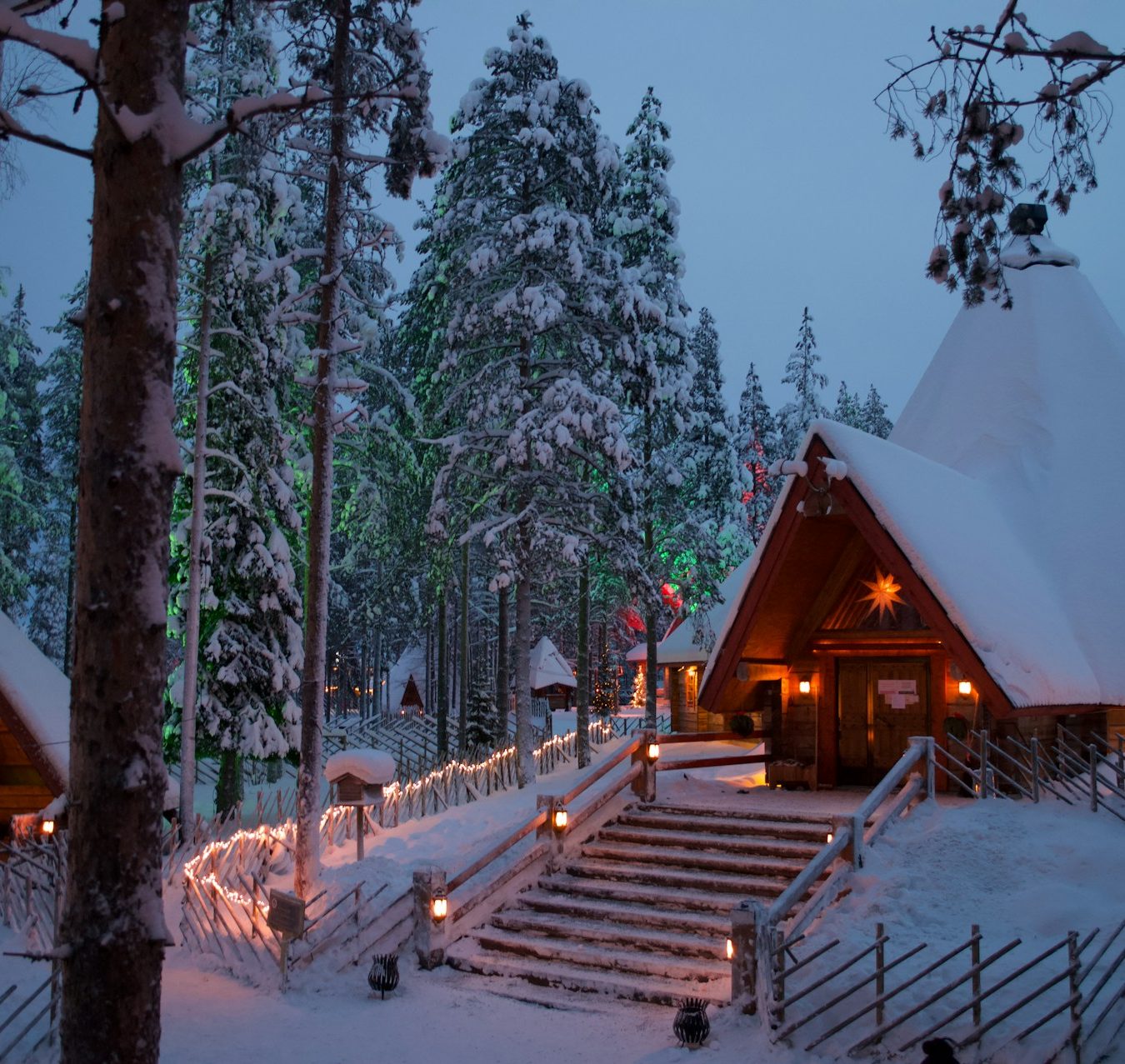 Chalets traditionnels au cœur d’une forêt enneigée en Laponie finlandaise.