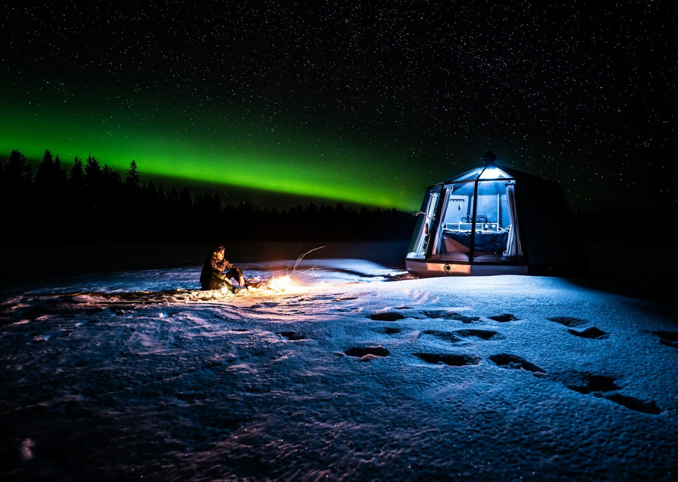 Aurores boréales au-dessus d’un hébergement vitré dans la neige en Laponie finlandaise.