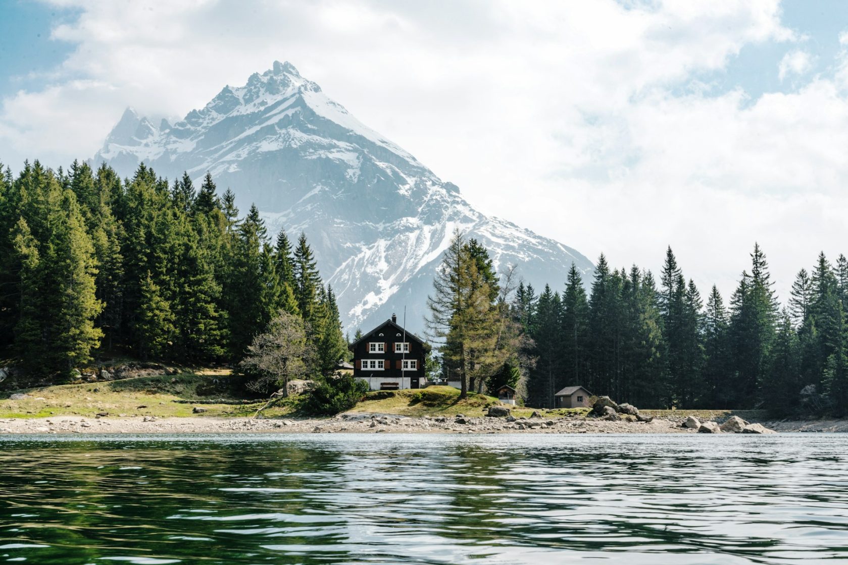Chalet traditionnel au bord d’un lac entouré de montagnes dans les Alpes suisses